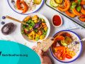 table with baked vegetables, fresh salad, berries, bread on a white background