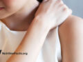 Woman holding upper shoulder as if in pain