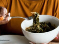 Person eating greens from a white bowl