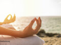 Close up of hands in a meditative pose on a beach