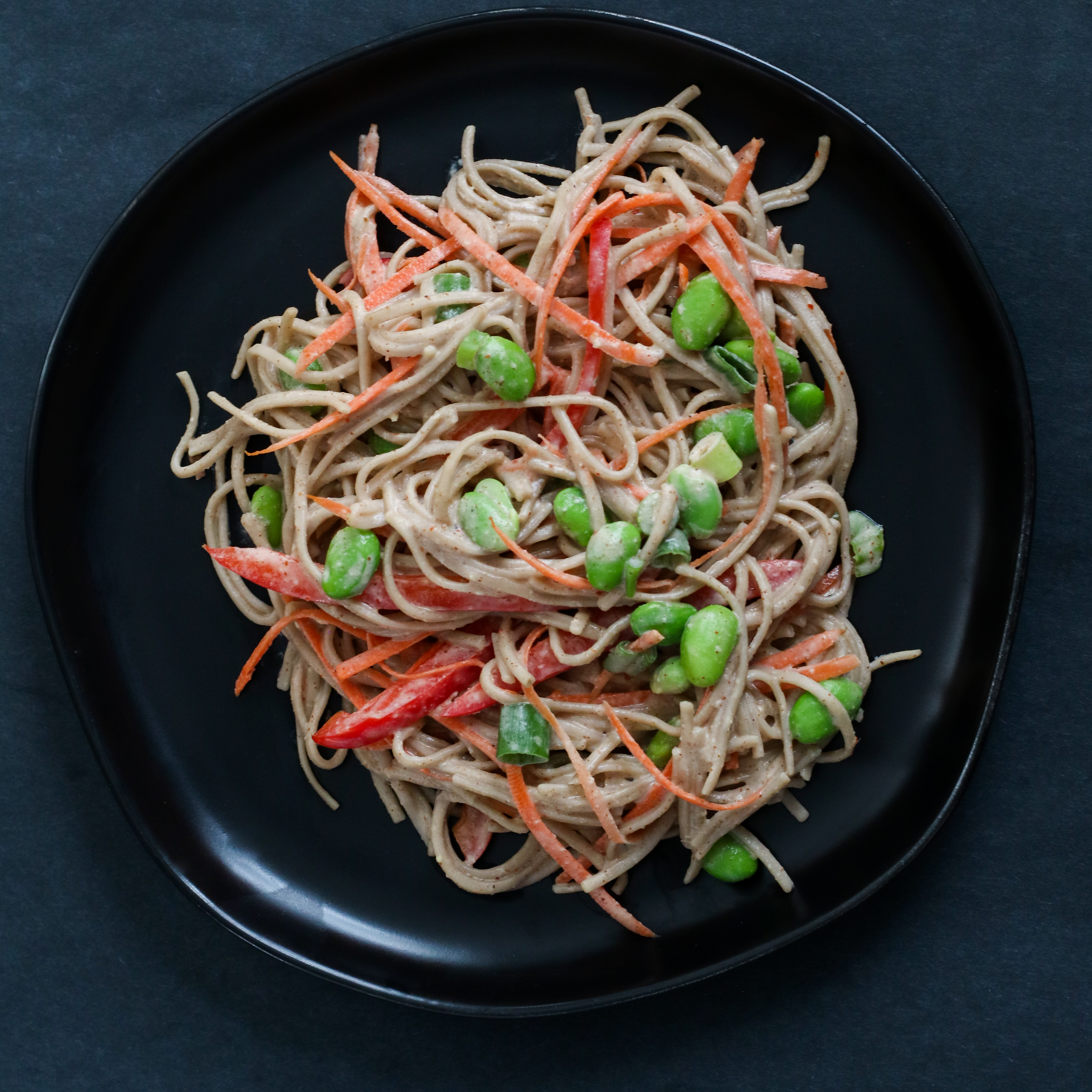 plate of soba noodles with almond butter sauce, edamame and vegetables