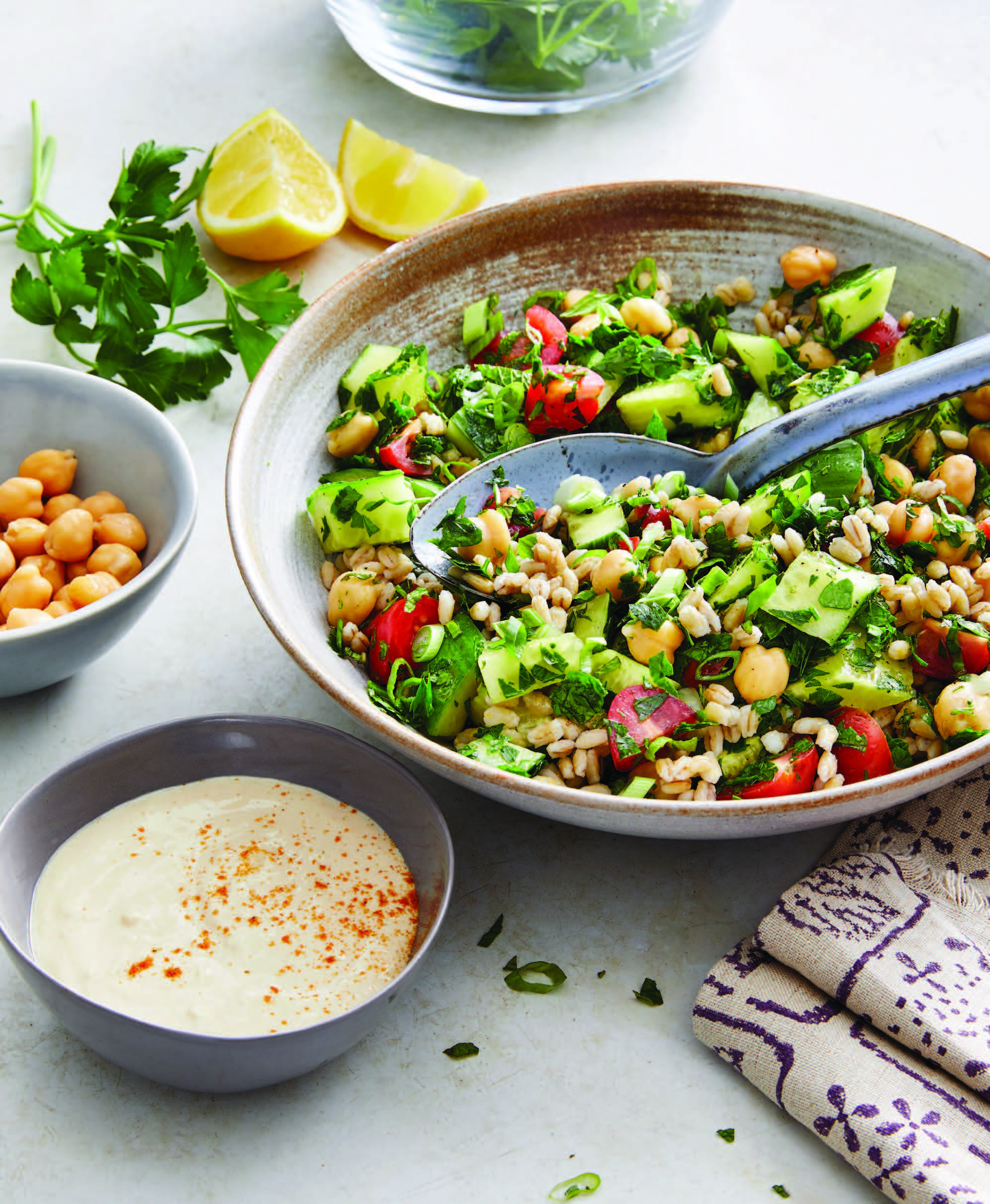 serving dish of barley tabbouli salad with chickpeas and a small dish of tahini sauce