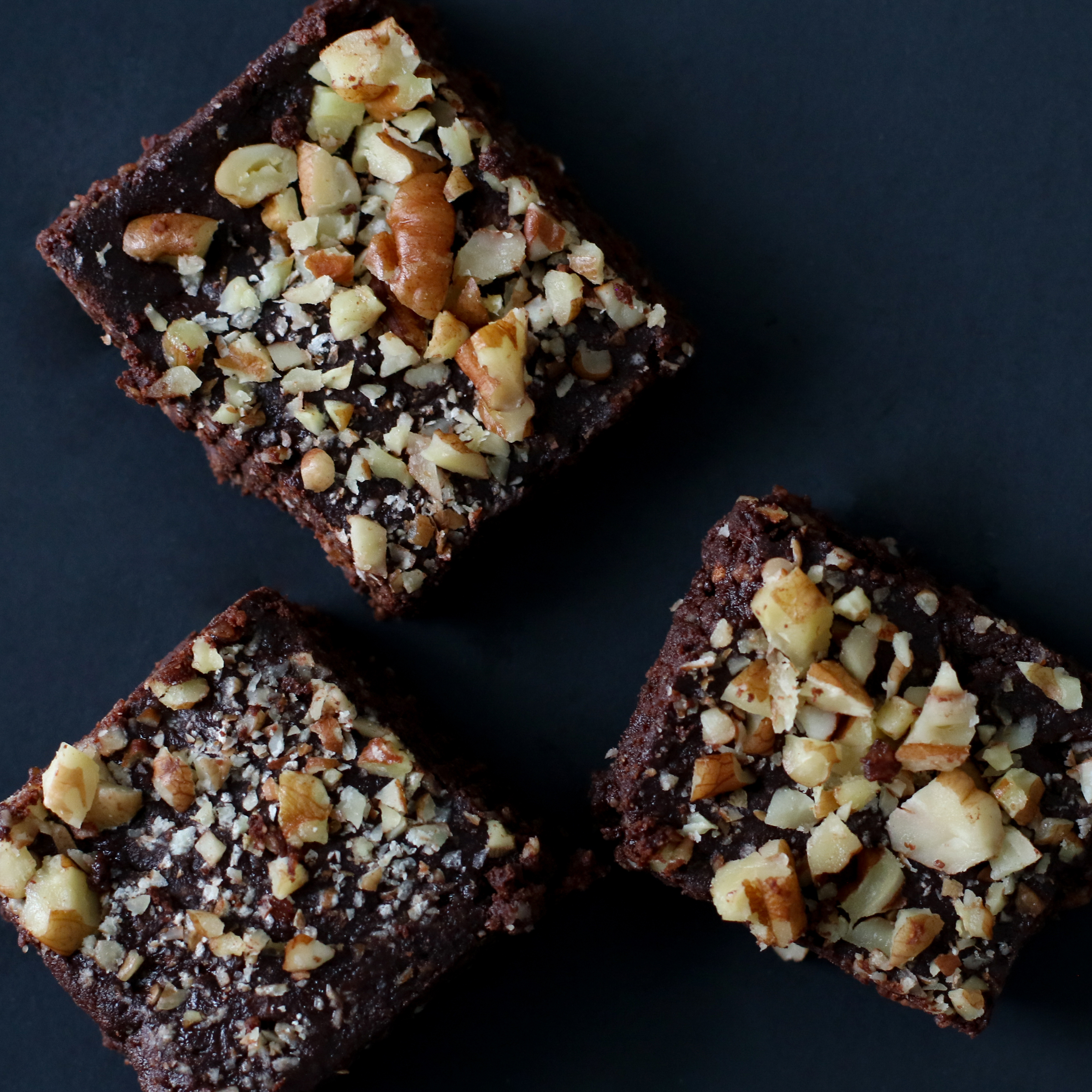 three squares of brownies topped with crushed nuts
