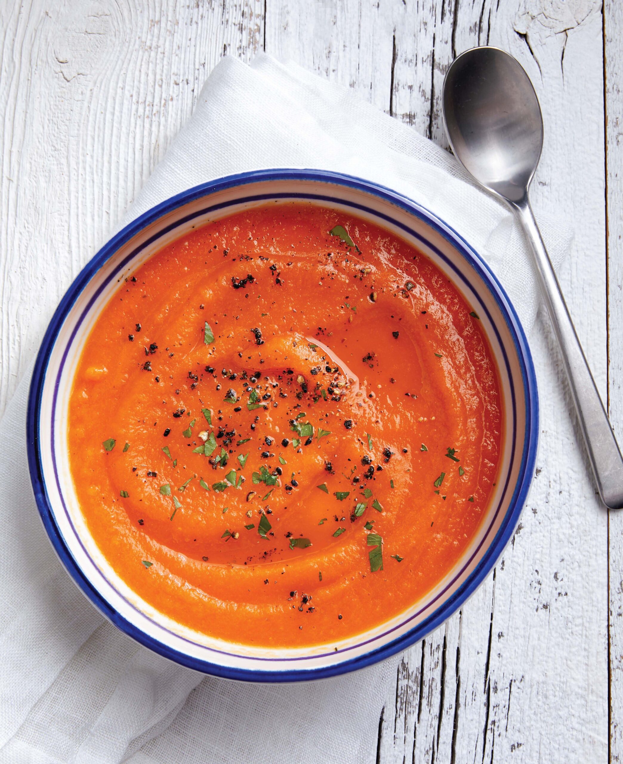 bowl of ginger carrot soup topped with herbs