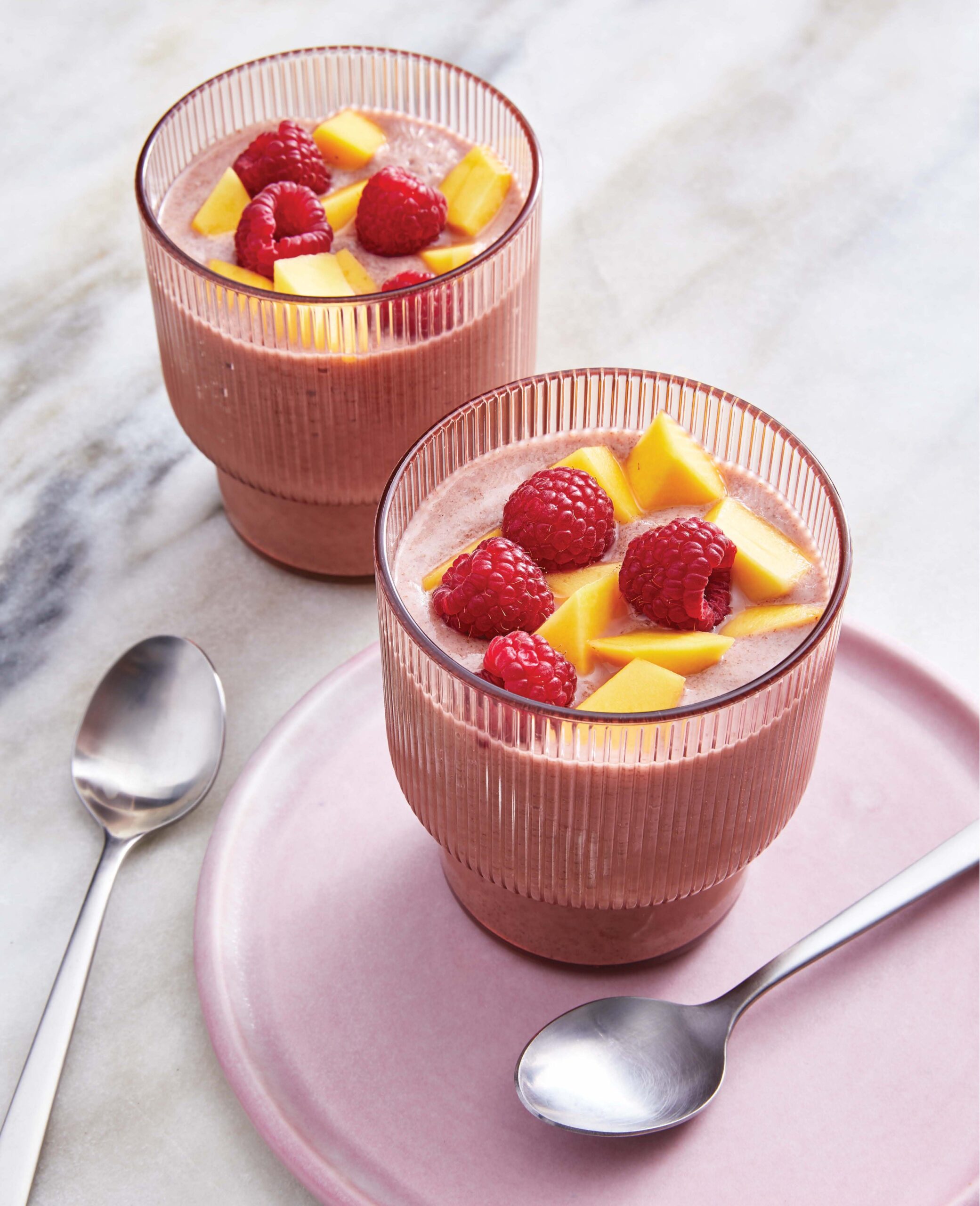 glasses filled with chia pudding topped with raspberries and mango