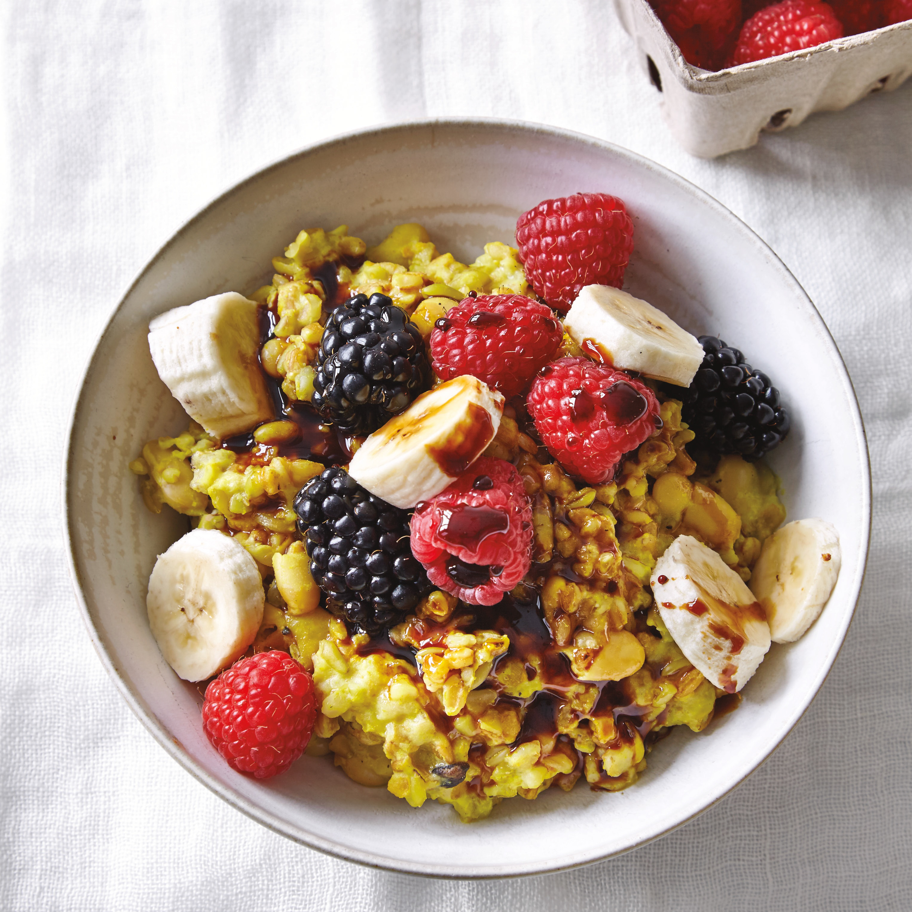 bowl of turmeric oats topped with sliced banana and berries