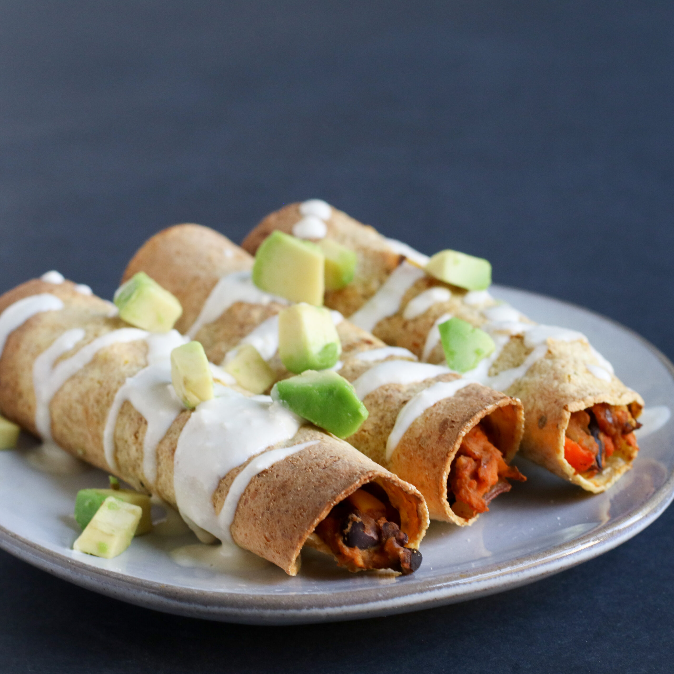 sweet potato taquitos topped with cashew cream and cubed avocado