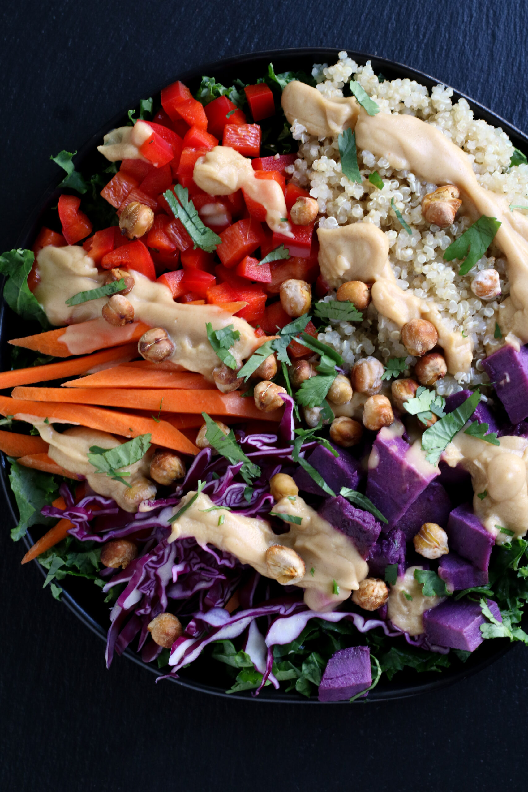 bowl of quinoa, chickpeas, and vegetables, topped with ultimate sauce