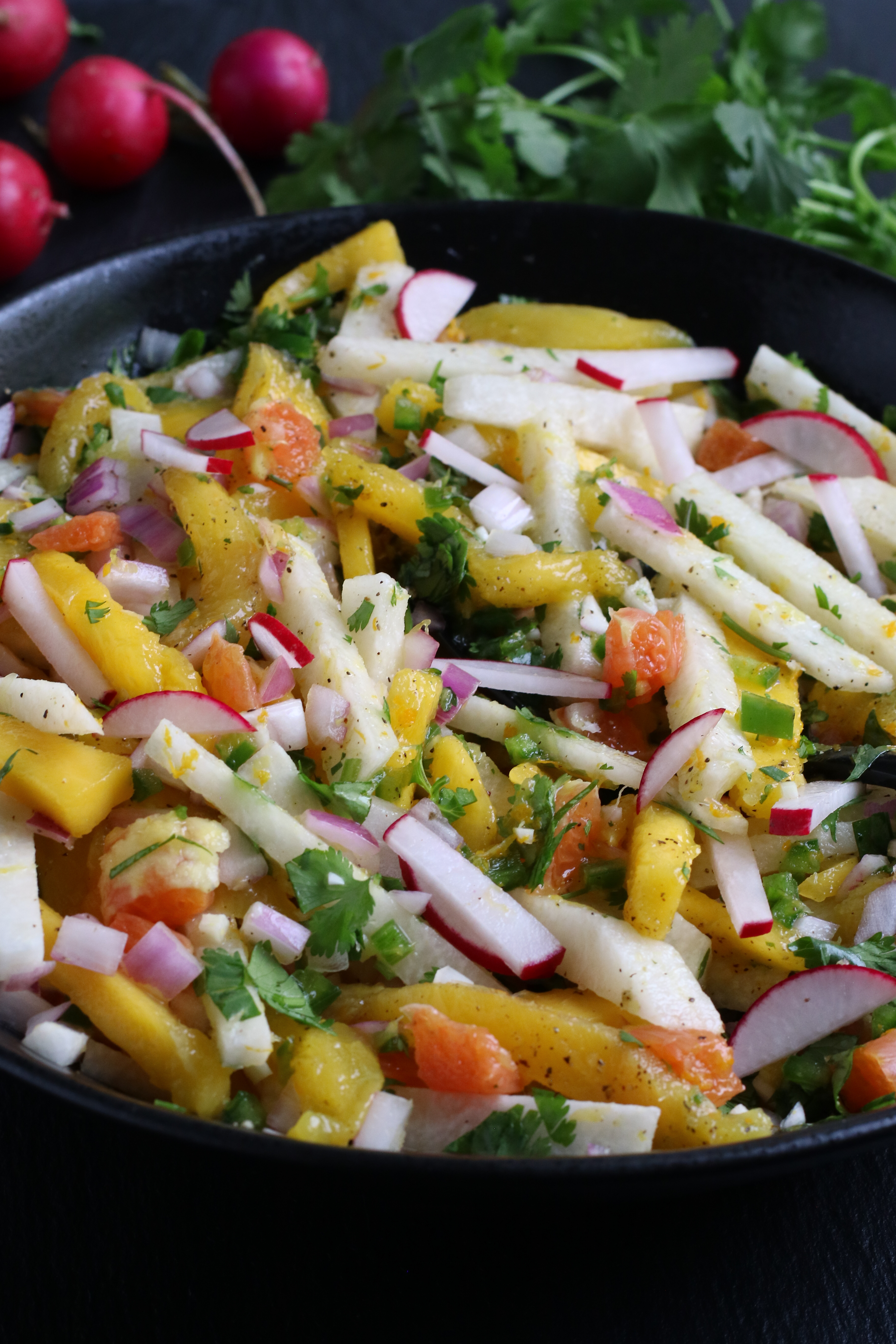 bowl of jicama mango salad topped with herbs