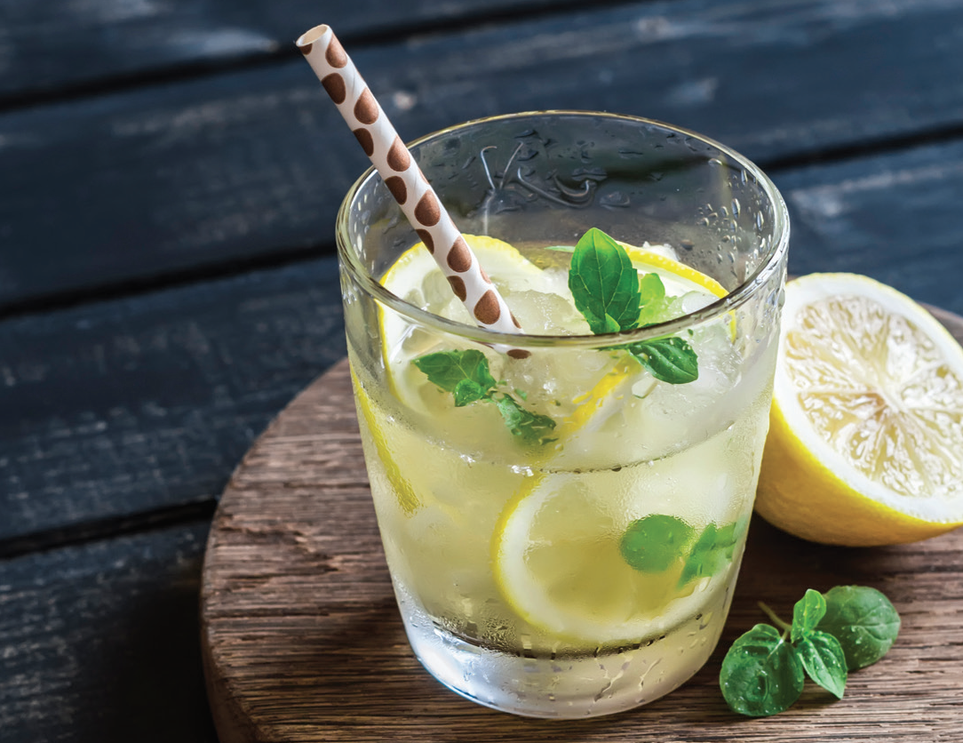 lemon ginger cooler in a glass with sliced lemon, mint and a paper straw