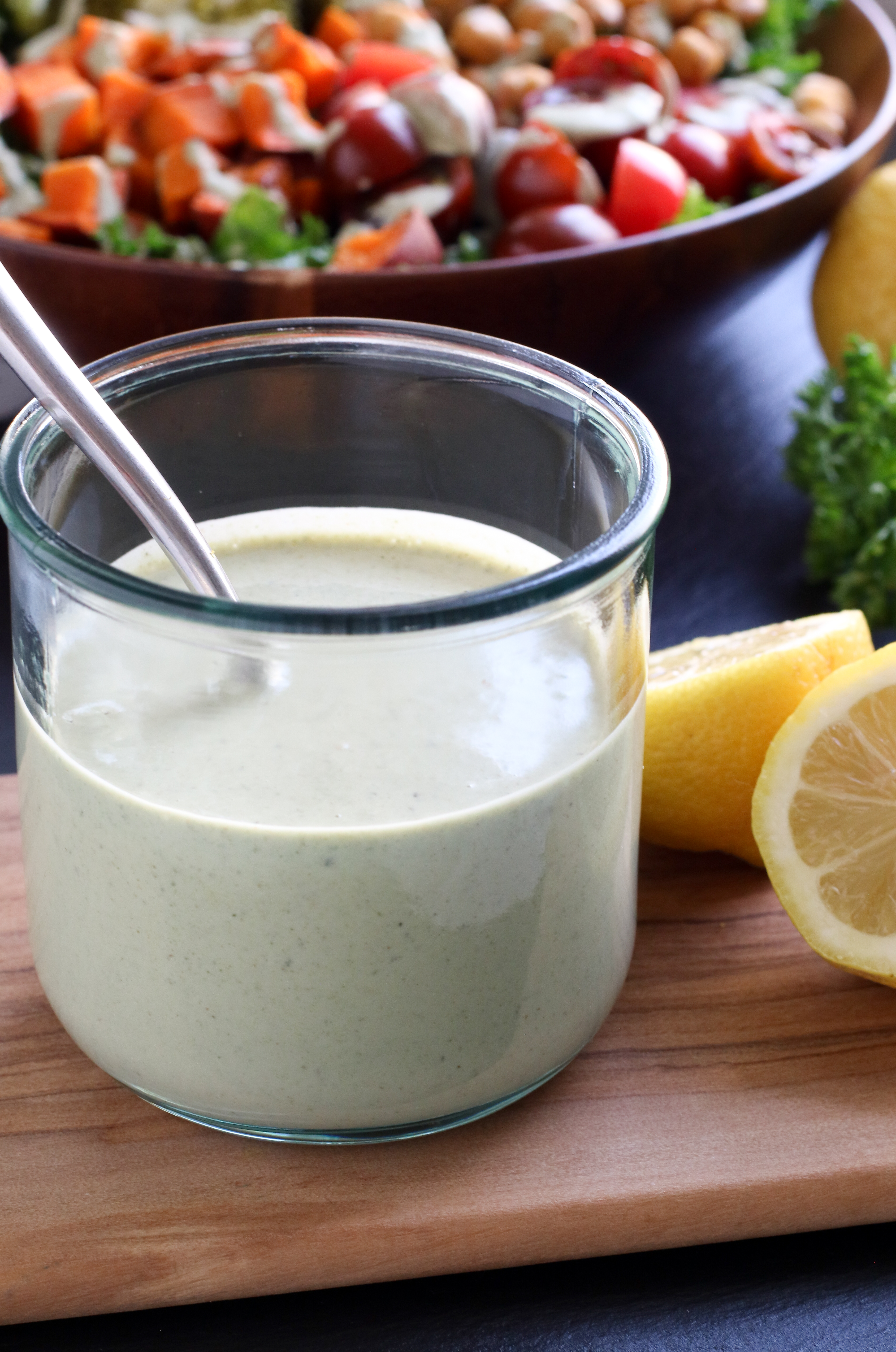 small jar of tahini sauce, with a bowl of vegetables in the background
