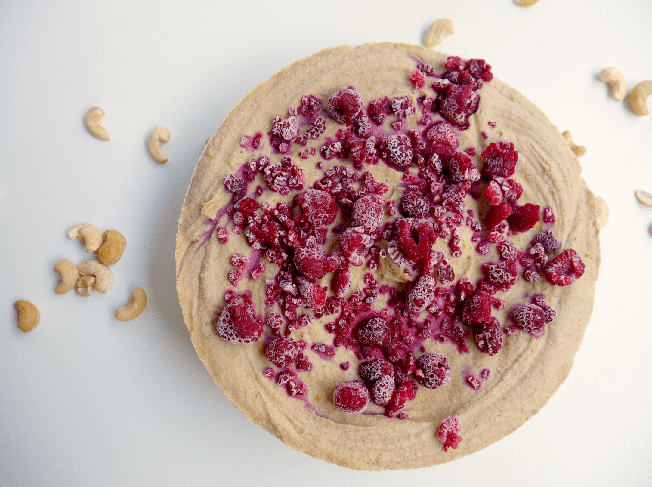 raw lemon cheesecake topped with frozen raspberries